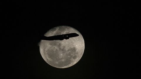 Un avi&oacute;n pasa frente a la luna llena en R&iacute;o de Janeiro, Brasil