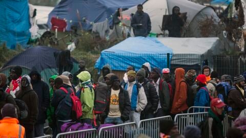 Varios migrantes esperan para su evacuaci&oacute;n en el centro de recepci&oacute;n de corta estancia en el campamento conocido como "La Jungla" durante su desmantelamiento en Calais