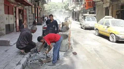Tres hombres recogen los escombros producidos tras el lanzamiento de un cohete en varios puntos del norte de Alepo, Siria Tres hombres recogen los escombros producidos tras el lanzamiento de un cohete en varios puntos del norte de Alepo, Siria