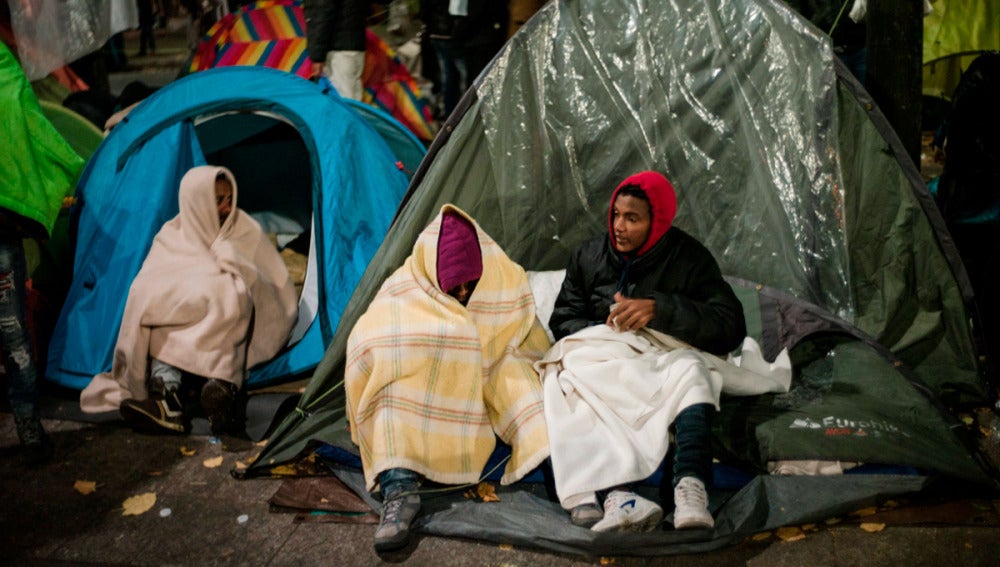 Inmigrantes esperan en sus tiendas de campaña antes del desalojo de un campamento en el distrito 19 de París, Francia