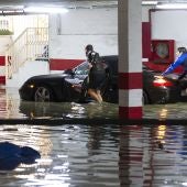 Varias personas intentan sacar el coche de un garaje inundado