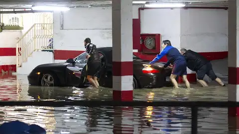 Varias personas empujan un vehículo en un garaje anegado por las fuertes lluvias Varias personas empujan un vehículo en un garaje anegado por las fuertes lluvias