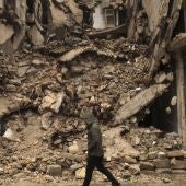 Un hombre camina junto a un edificio derruido en el barrio de al-Mashad en la zona controlada por los rebeldes 