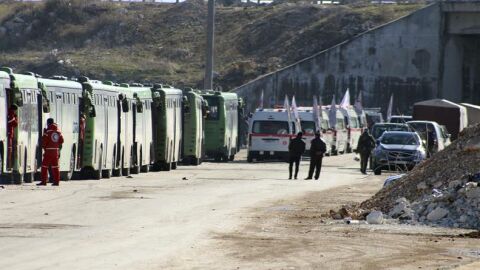  Varios operarios de autobuses y ambulancias esperan a comenzar la evacuaci&oacute;n de los combatientes, sus familiares y civiles que se encuentran en los barrios rebeldes en Alepo