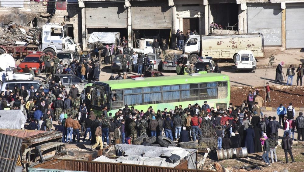 Civiles, combatientes y sus familiares accediendo a uno de los autobuses durante los trabajos de evacuación de los barrios rebeldes de Alepo