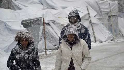 Varios refugiados caminan bajo la nieve en el campamento de refugiados de Moria Varios refugiados caminan bajo la nieve en el campamento de refugiados de Moria