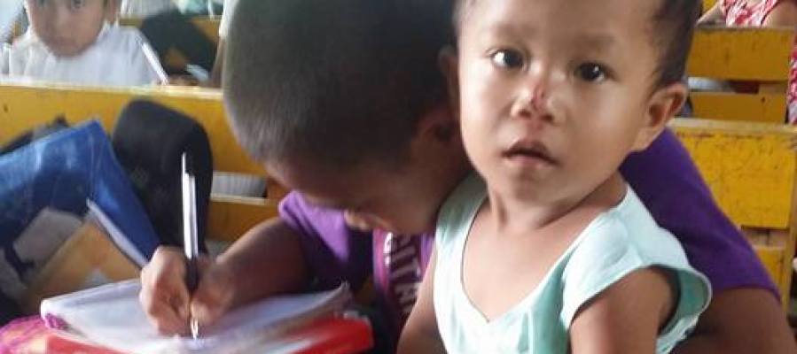 Un niño filipino de nueve años con su hermano de dos en la escuela Un niño filipino de nueve años con su hermano de dos en la escuela