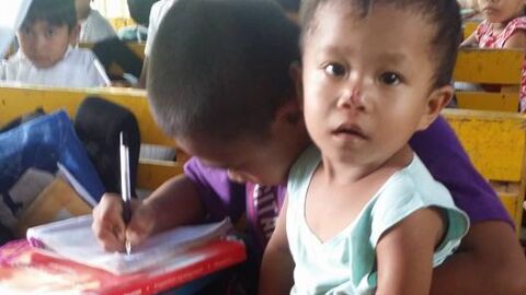 Un ni&ntilde;o filipino de nueve a&ntilde;os con su hermano de dos en la escuela