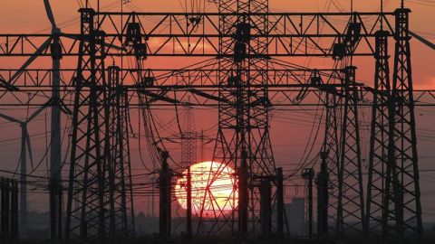 En la imagen, una puesta de sol junto a un tendido el&eacute;ctrico y unos molinos de viento