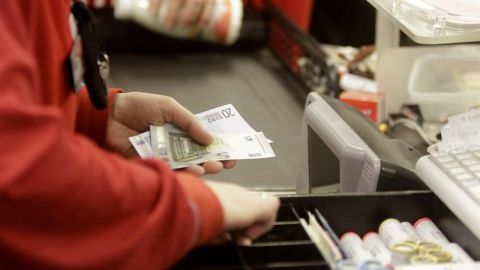 Una cajera de un supermercado devolviendo dinero a un cliente