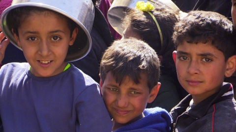 Unos ni&ntilde;os del campamento de desplazados de Yibrin, en Alepo, hacen cola para recoger comida.