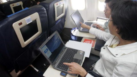 Dos pasajeros utilizando el ordenador port&aacute;til en un vuelo