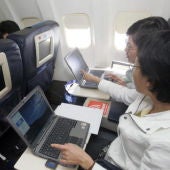 Dos pasajeros utilizando el ordenador portátil en un vuelo