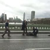 varias personas mientras atienden a un herido tras un tiroteo en el Wetminster Bridge junto al Parlamento en Londres