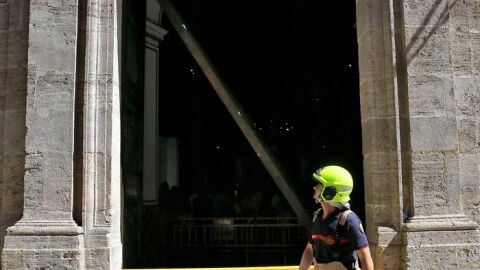 Un bombero observa la puerta de la Bas&iacute;lica de Valencia que se ha descolgado