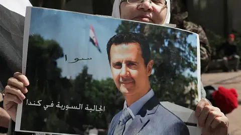 Una mujer sostiene un cartel con la imagen de Bashar al Assad Una mujer sostiene un cartel con la imagen de Bashar al Assad