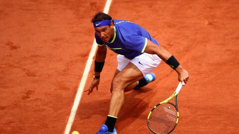 Rafa Nadal, desliz&aacute;ndose sobre la central de Roland Garros ejecutando una bola cortada