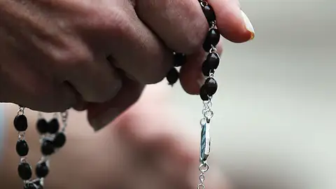 Una mujer con un rosario en la mano Una mujer con un rosario en la mano