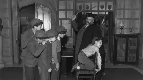 Castigo a un niño con una regla de madera Castigo a un niño con una regla de madera