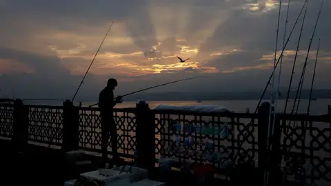 Pesca en el puente Galata (16/08/2017) Hombre pescando durante una puesta de sol en el puente Galata en Estambul (Turquía).
