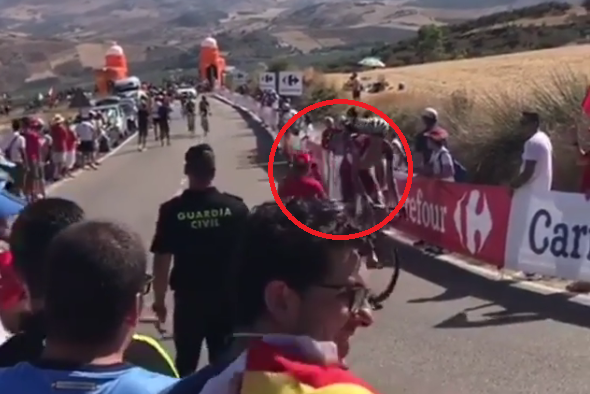 Un aficionado con discapacidad empuja a un ciclista en plena etapa de la Vuelta a España Un aficionado con discapacidad empuja a un ciclista en plena etapa de la Vuelta a España