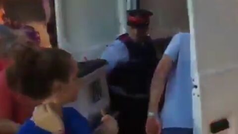 Un Mosso d'Esquadra guarda una urna llena de papeletas en una furgoneta