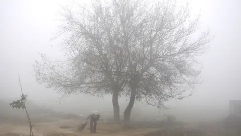 El árbol de la niebla (11-11-2017) Un hombre indio barre el suelo con neblina y niebla a primera hora de la mañana en las afueras de Amritsar, India