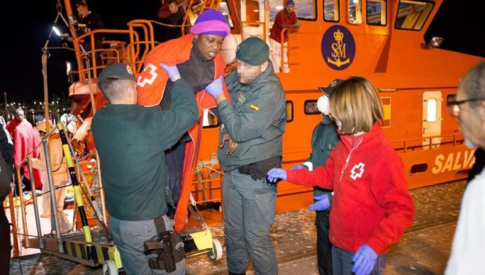 Miembros de la Guardia Civil y de la Cruz Roja ayudan a desembarcar a un inmigrante