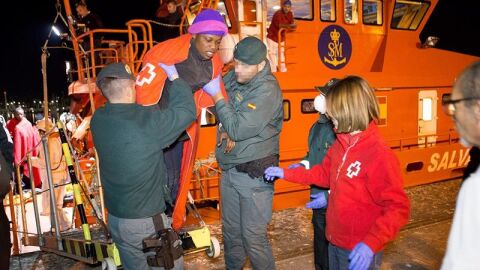 Miembros de la Guardia Civil y de la Cruz Roja ayudan a desembarcar a un inmigrante
