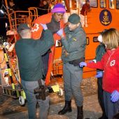 Miembros de la Guardia Civil y de la Cruz Roja ayudan a desembarcar a un inmigrante