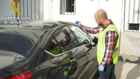 Un agente de la Guardia Civil junto a uno de los veh&iacute;culos afectados por los actos vand&aacute;licos de los menores detenidos