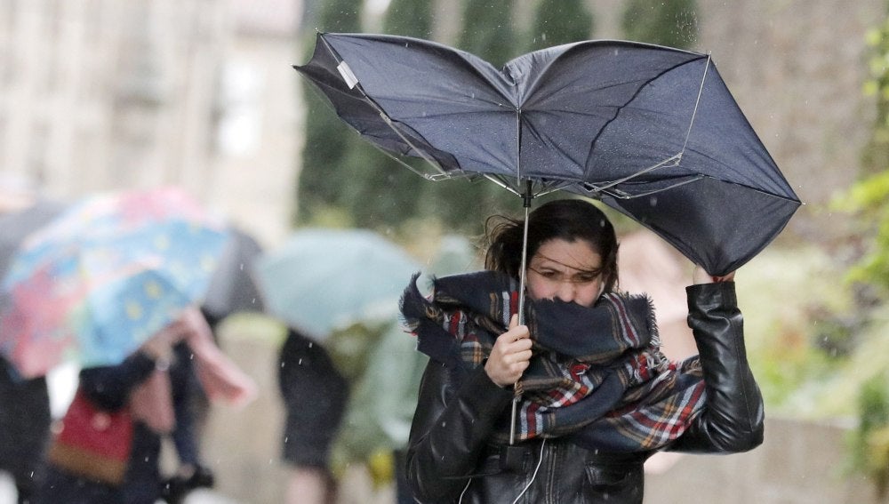 Una mujer combate los fuertes vientos y la lluvia