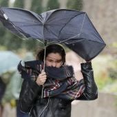Una mujer combate los fuertes vientos y la lluvia