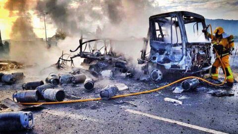 Un bombero en las labores de extinci&oacute;n del cami&oacute;n de butano incendidado en Aspe