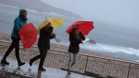 Tres mujeres se protegen de la lluvia en el paseo mar&iacute;timo de A Coru&ntilde;a