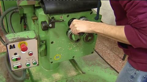 Un trabajador manipula una m&aacute;quina en una f&aacute;brica