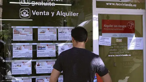Un hombre mira los pisos en venta de una inmobiliaria Un hombre mira los pisos en venta de una inmobiliaria