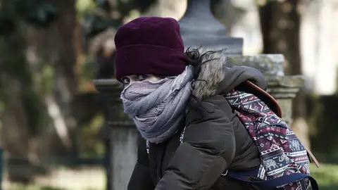 Una joven montada en su bicicleta se protege del frío Una joven montada en su bicicleta se protege del frío
