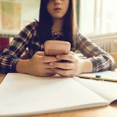 Una adolescente mira su móvil en clase Una adolescente mira su móvil en clase