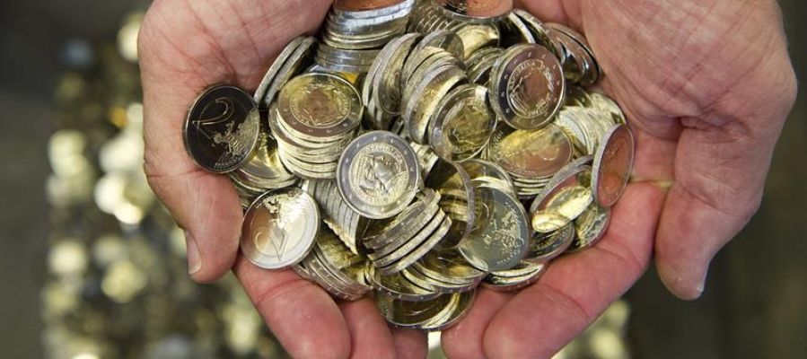 Un hombre sostiene varias monedas de euro Un hombre sostiene varias monedas de euro