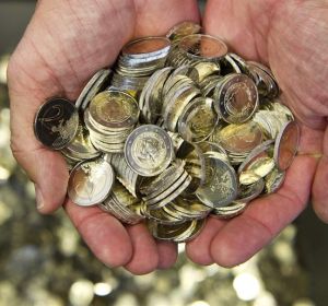 Un hombre sostiene varias monedas de euro Un hombre sostiene varias monedas de euro