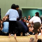 Varias mujeres tratan de reanimar a un hombre desfallecido en un ring de sumo