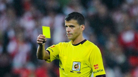 Gil Manzano muestra una tarjeta amarilla durante un partido