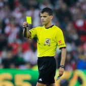 Gil Manzano muestra una tarjeta amarilla durante un partido