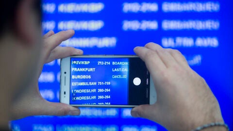 Un viajero fotograf&iacute;a el panel de salidas en el aeropuerto de El Prat