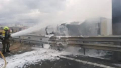 Bomberos trabajando en la extinción del incendio de la cabina del camion accidentado en Elche Bomberos trabajando en la extinción del incendio de la cabina del camion accidentado en Elche