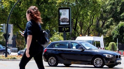 Una joven pasa junto a un term&oacute;metro que marca 35 grados cent&iacute;grados