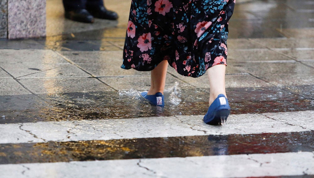 Imagen de una mujer cruzando bajo fuertes lluvias