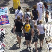 Unos turistas pasean por Las Ramblas de Barcelona entre varios manteros