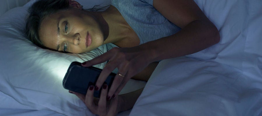 Una mujer mira el móvil antes de dormir Una mujer mira el móvil antes de dormir
